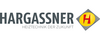 Logo von Hargassner, einem Unternehmen für Heiztechnik. Der Schriftzug „HARGASSNER“ ist in großen, grauen Buchstaben dargestellt, gefolgt von dem Slogan „HEIZTECHNIK DER ZUKUNFT“ in kleineren Buchstaben darunter. Ein gelbes Quadrat mit dem roten Buchstaben „H“ ist daneben zu sehen.